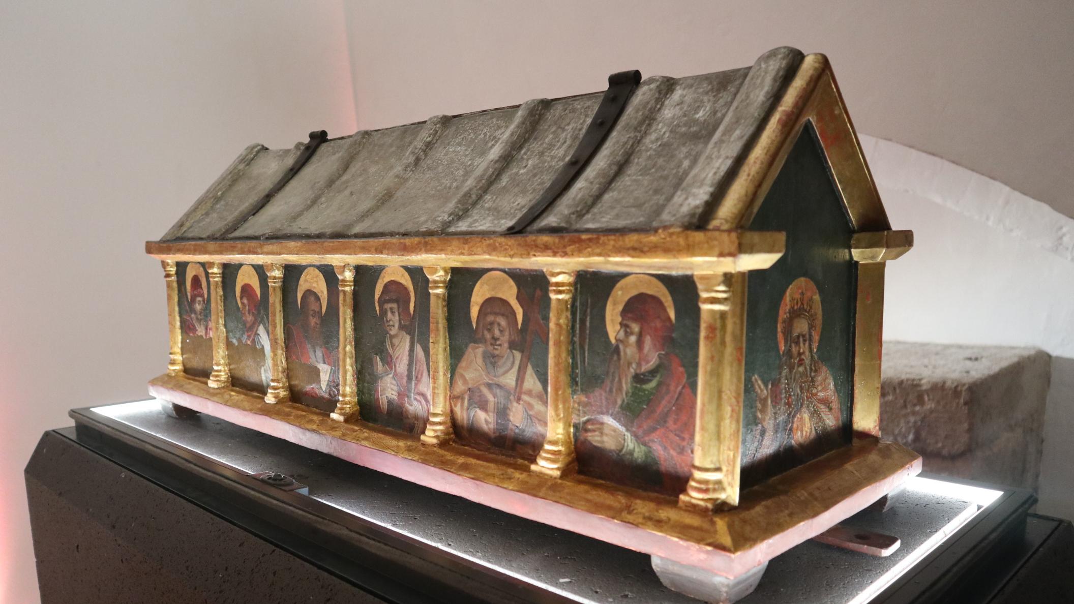 Eine kunstvollverzierte Holzkiste mit Heiligenfiguren daraufgemalt.